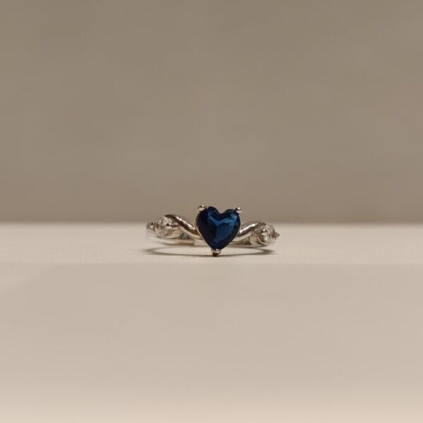 Anillo con circonia azul en forma de corazon y circonias blancas a los lados
